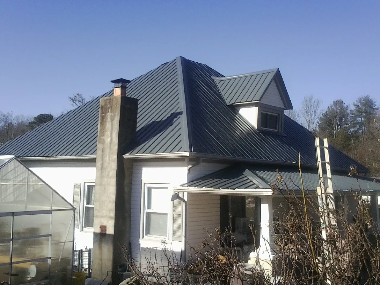 Dark blue standing seam metal roof on a white farmhouse with dormer — Slate & Tile Roof Repair by Roofing Brothers in Rockaway