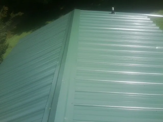 New green metal panels meeting at the ridge of a roof — Flat Roof Repair work by our crew in Rockaway