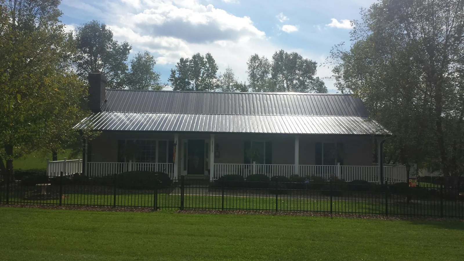 Gray metal roof on a brick ranch with a full width front porch — Gutter Guard Installation work by our crew in Rockaway