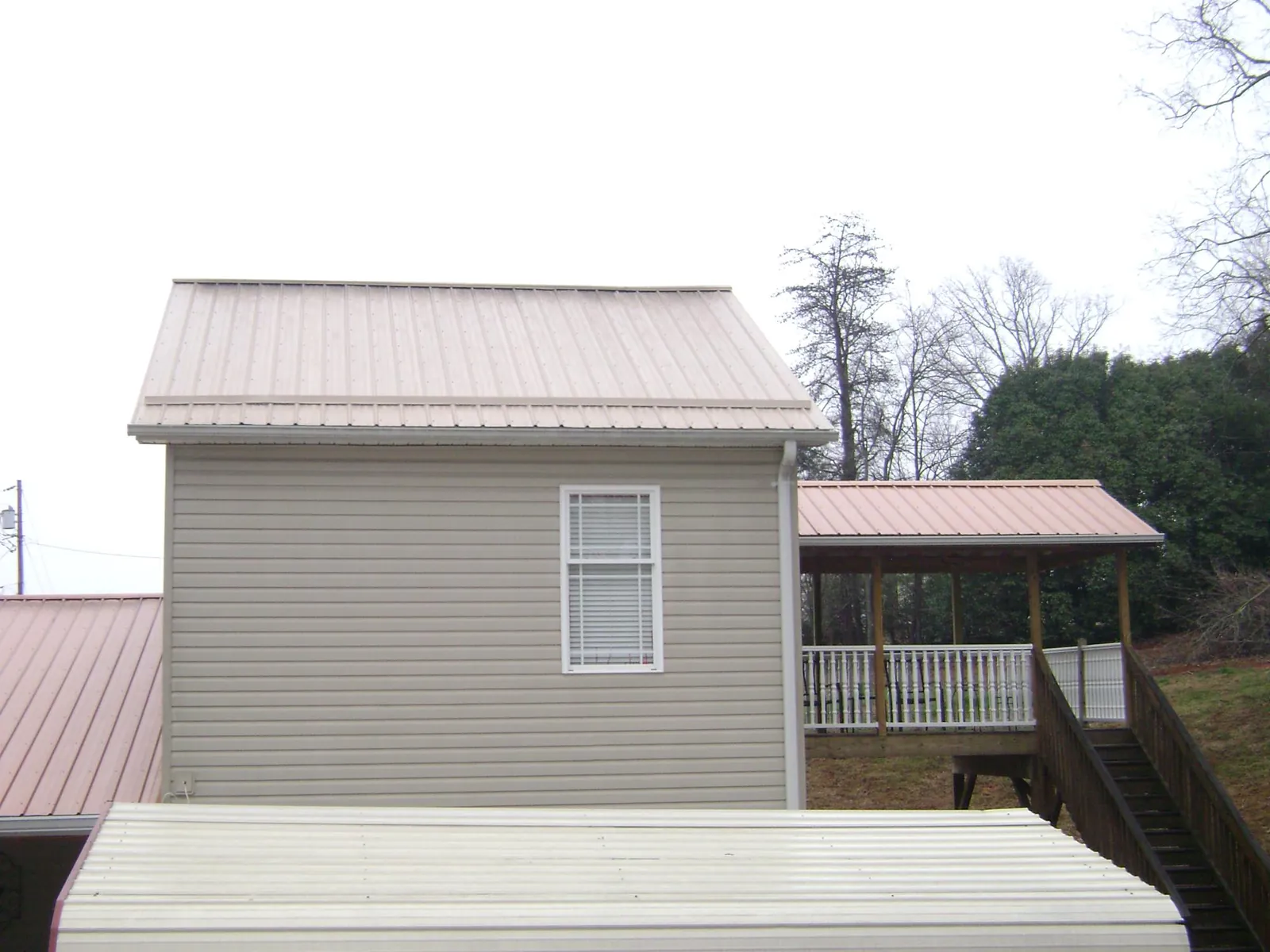 Tan metal roofs on a two story addition and attached porch, from a Roof Replacement job in Rockaway