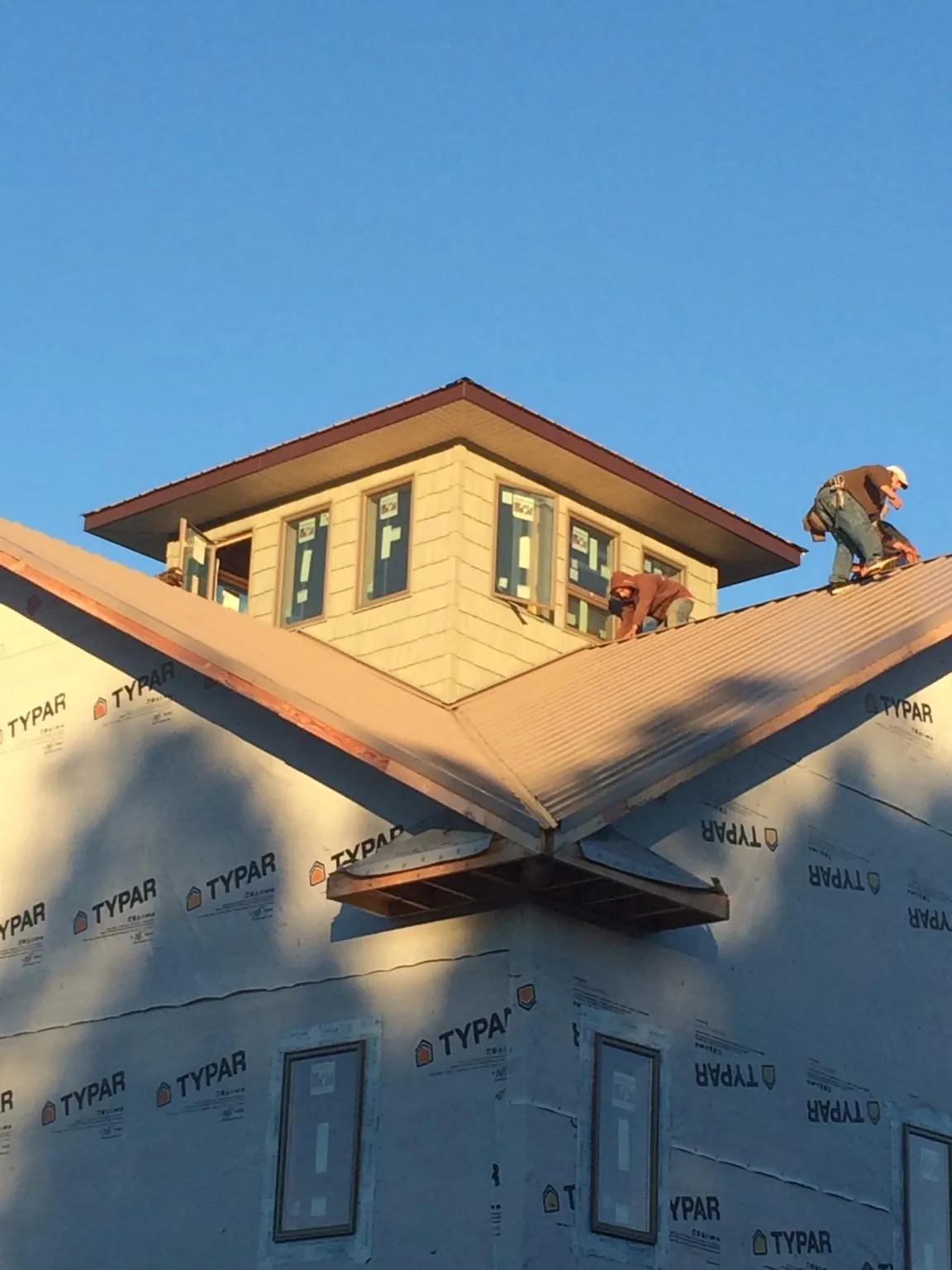 Roofers working around a rooftop cupola on a new metal roof at sunset — Roof Waterproofing in Rockaway by Roofing Brothers